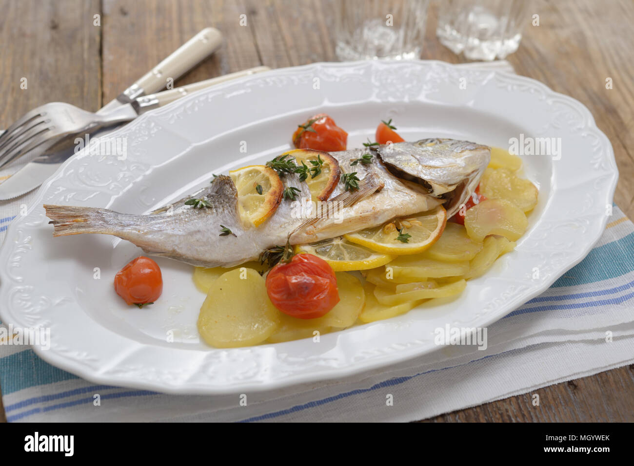 Baked sea bream with vegetables on an oval dish Stock Photo