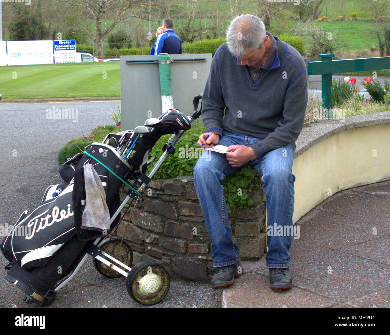 adult male golfer checking his score card after playing an 18 hole competition to ensure the correct score is registered on the golf clubs register. Stock Photo