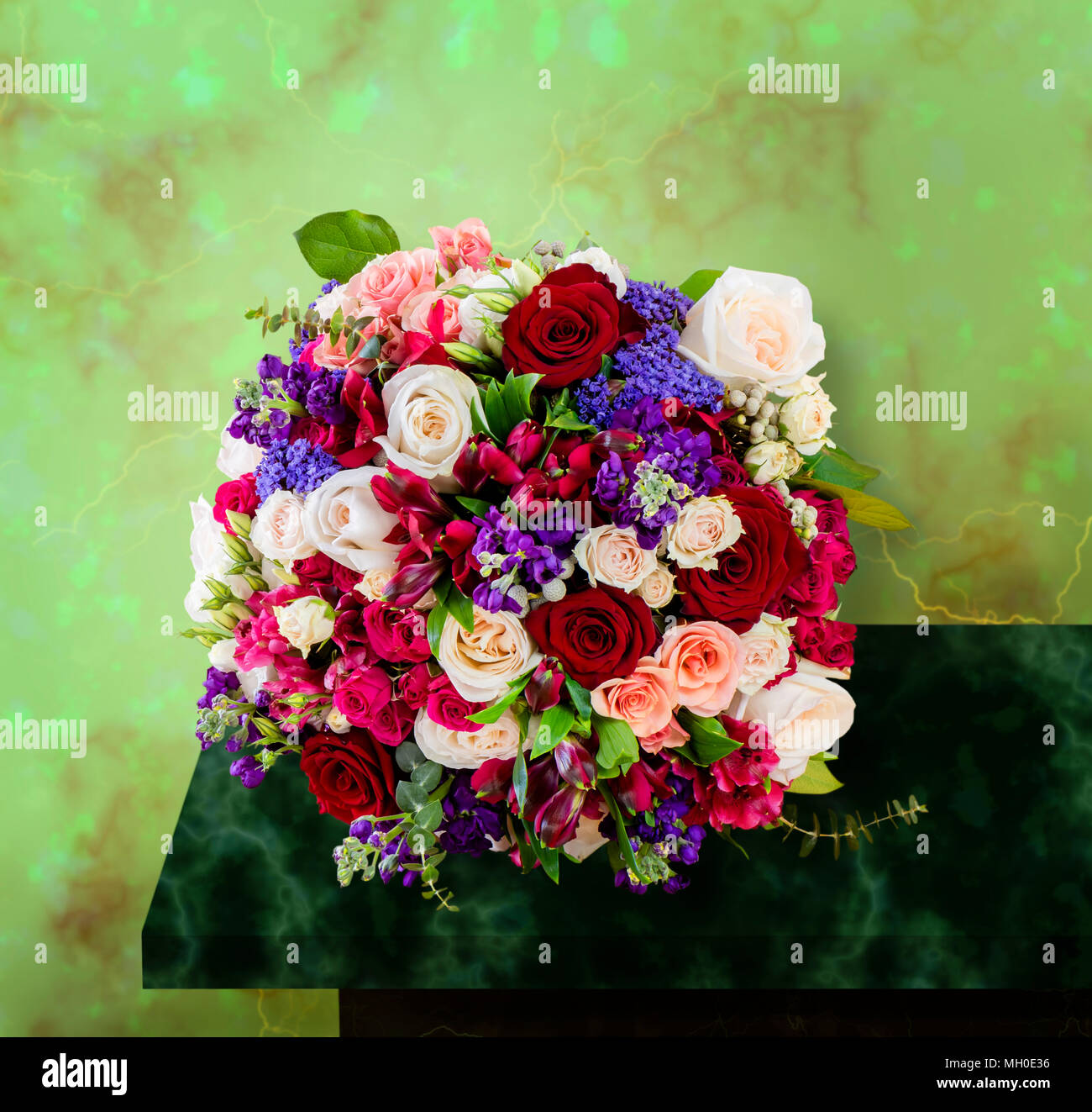 top view of a beautiful bouquet of flowers, multi-colored roses with green leaves, standing on a marble table Stock Photo