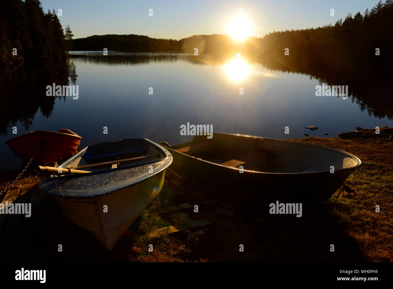 Evening sun sets on Norwegian lake with small boats in foreground at Nordbysjøen near Lillestrøm and Oslo, Norway Stock Photo