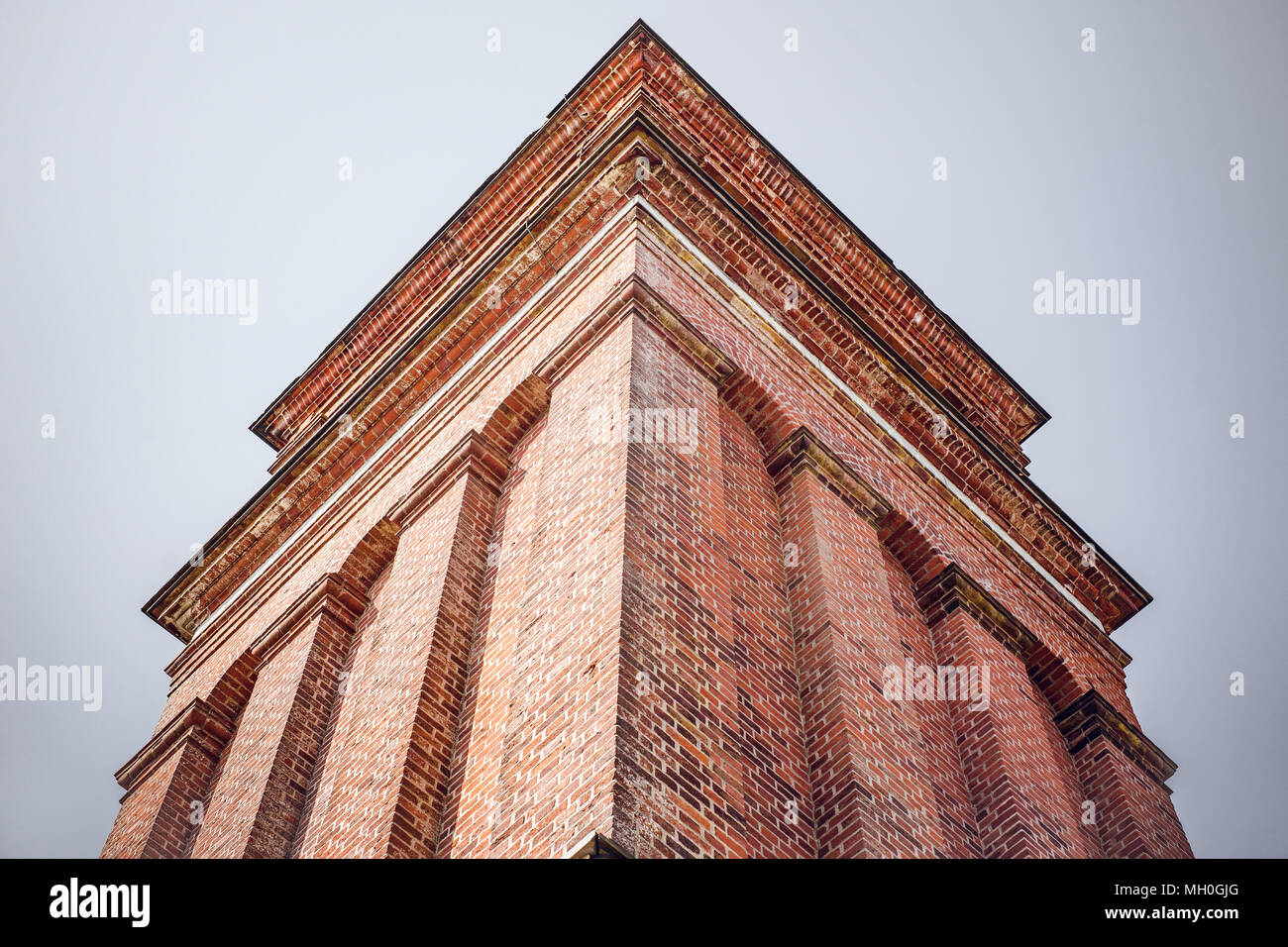High tower with red bricks from below on a grey and blue background Stock Photo