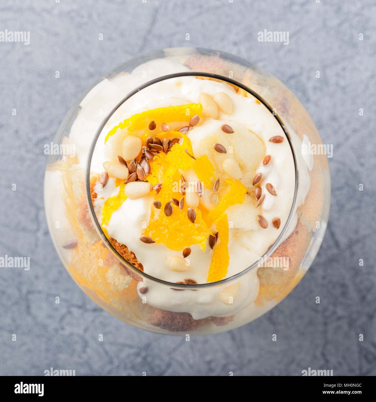 Glass with Healthy homemade layered dessert trifle with orange, biscuit