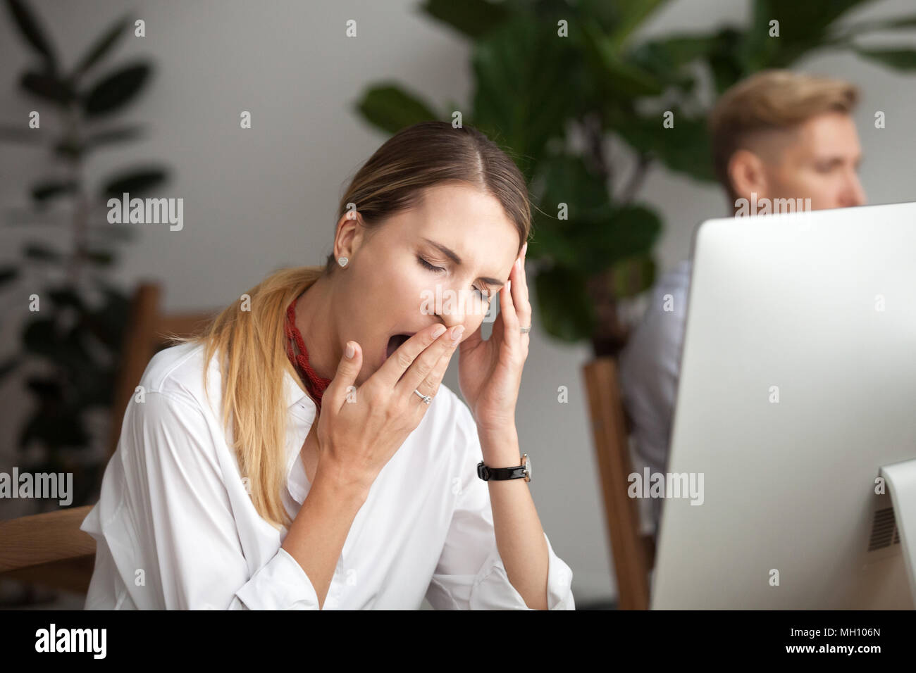 Bored tired businesswoman yawning at workplace feeling lack of s Stock Photo