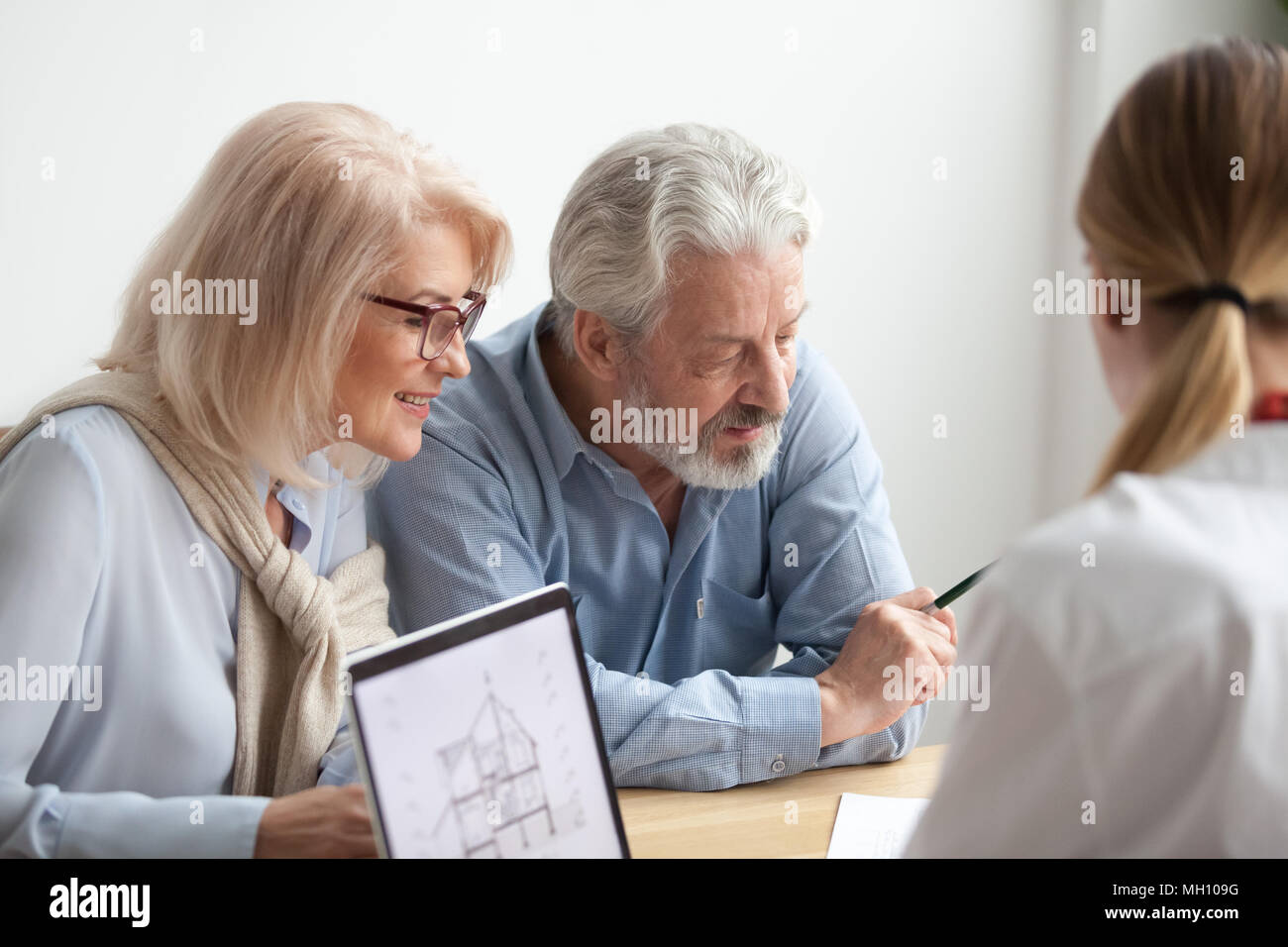 Older couple reading contract at meeting with real estate agent Stock