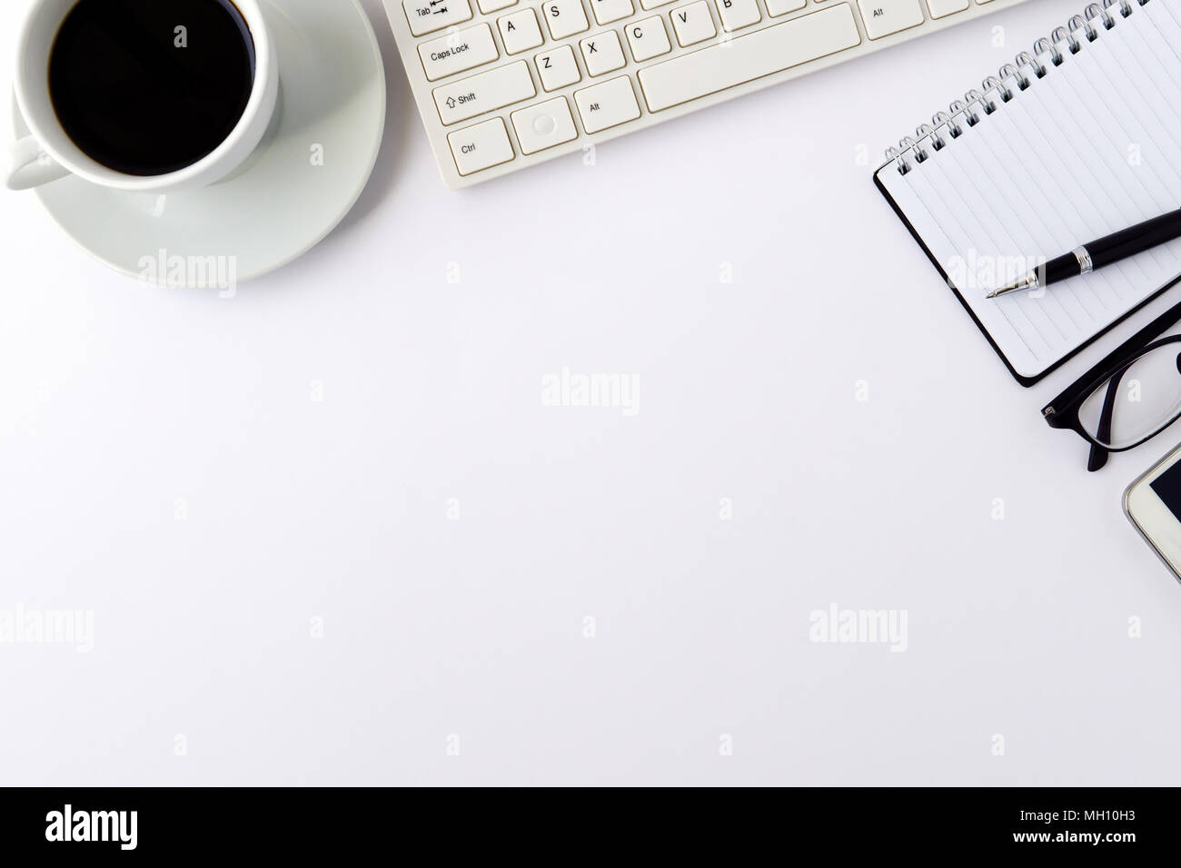Office desk table with blank notebook page with pen, computer keyboard and cup of coffee. Top view, flat lay. Stock Photo