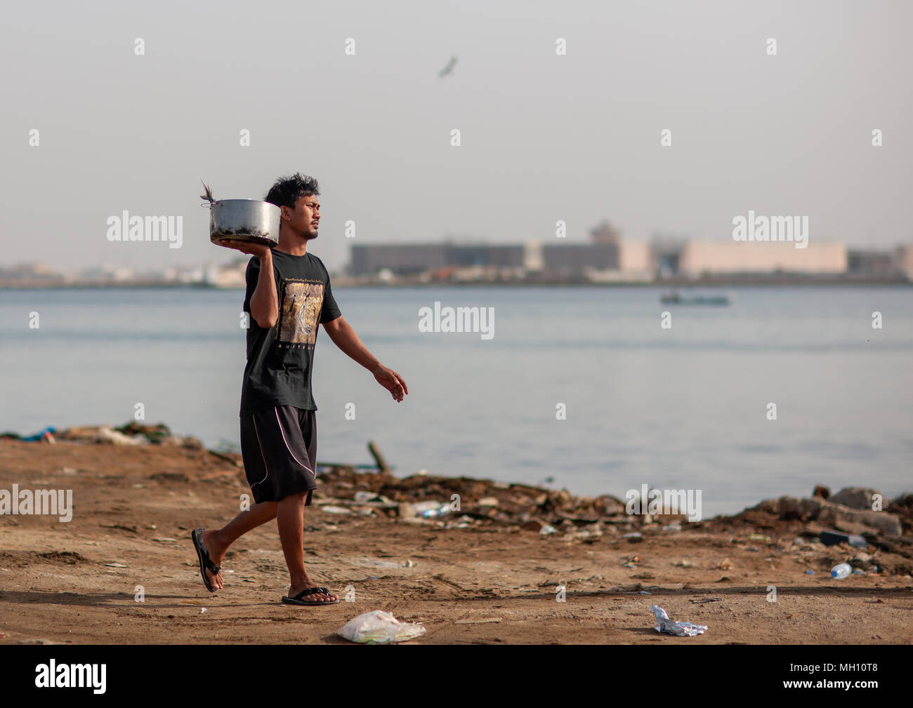 Asian foreign worker carrying fish, Jizan Region, Jizan, Saudi Arabia Stock Photo