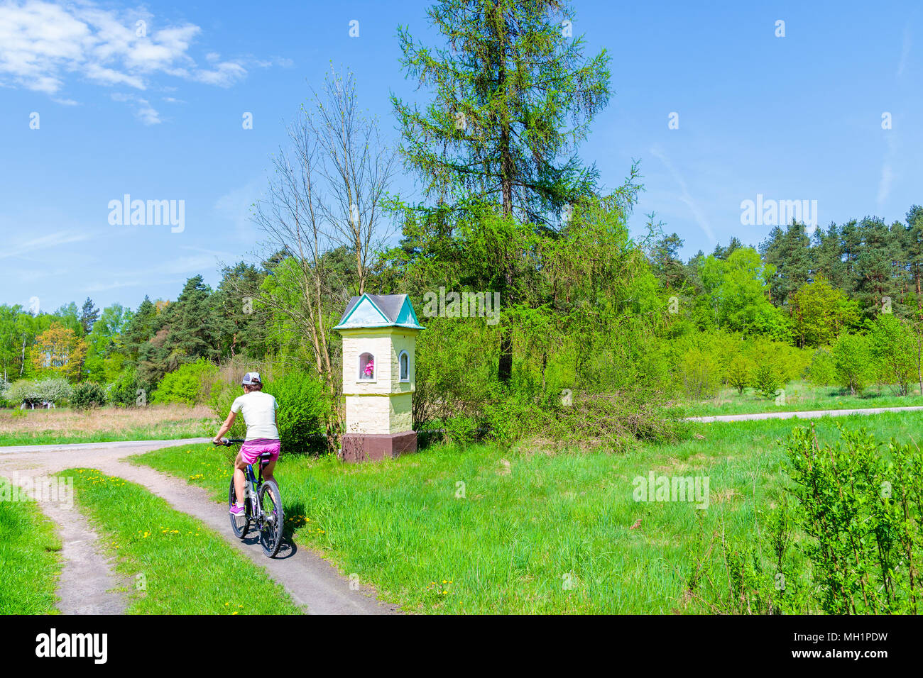 Young woman cycling on rural road near Krakow city during spring season, Poland Stock Photo