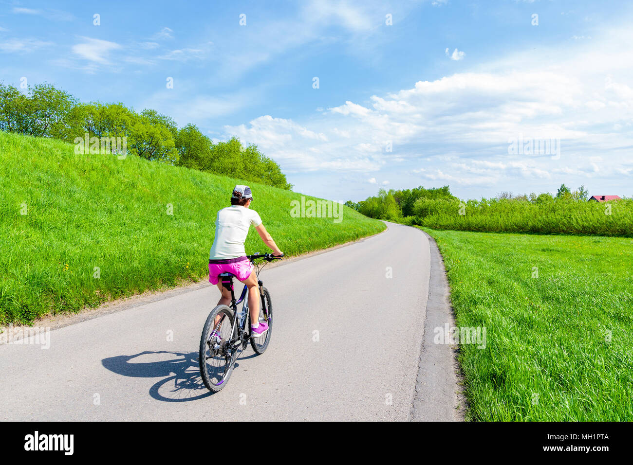 Young woman cycling on rural road along Vistula river near Krakow city during spring season, Poland Stock Photo