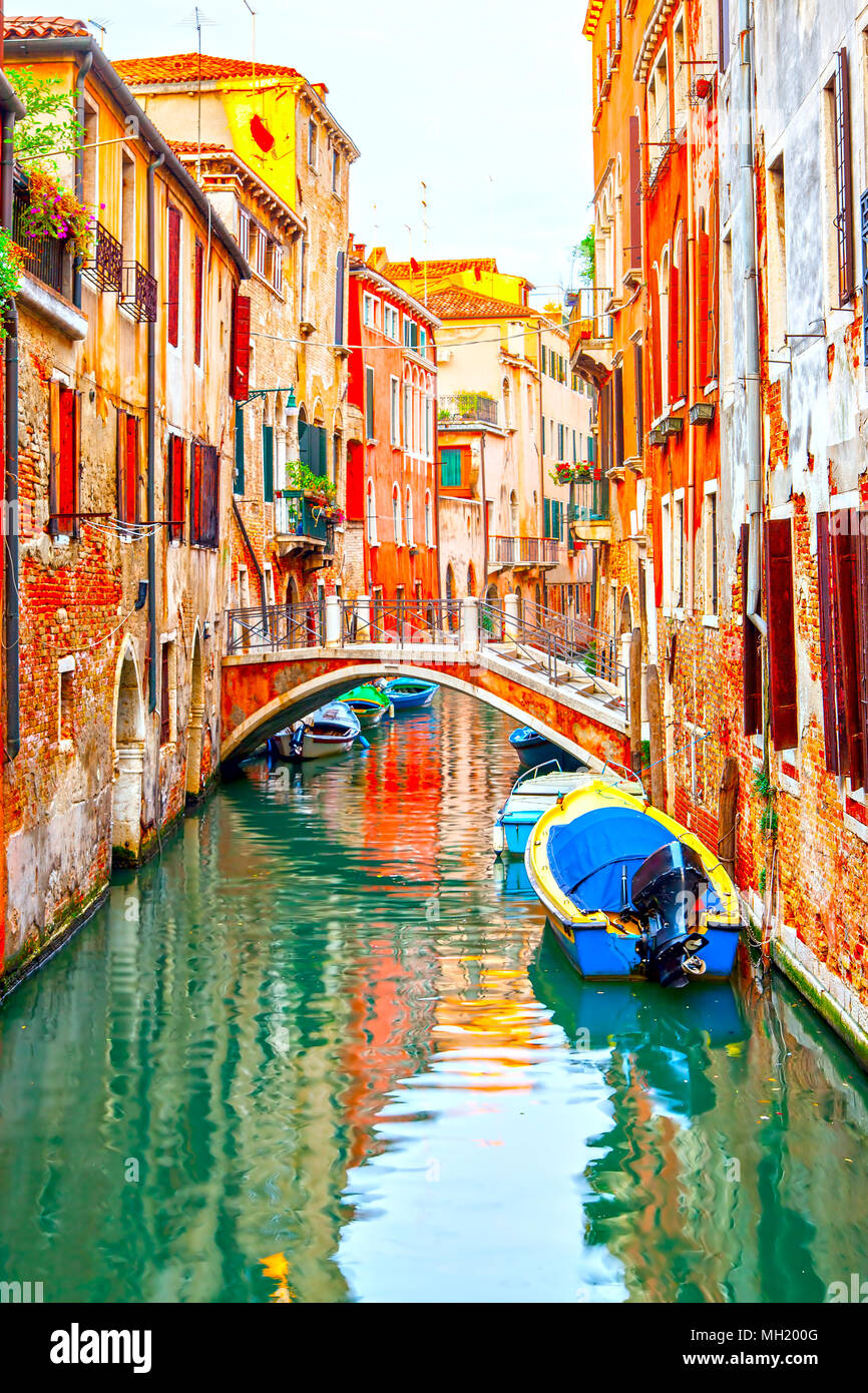 Narrow canal with small bridge and motorboats in Venice, Italy Stock Photo