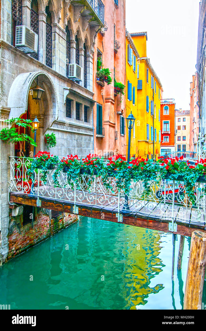 Small bridge with flowers over narrow canal in Venice, Italy Stock Photo