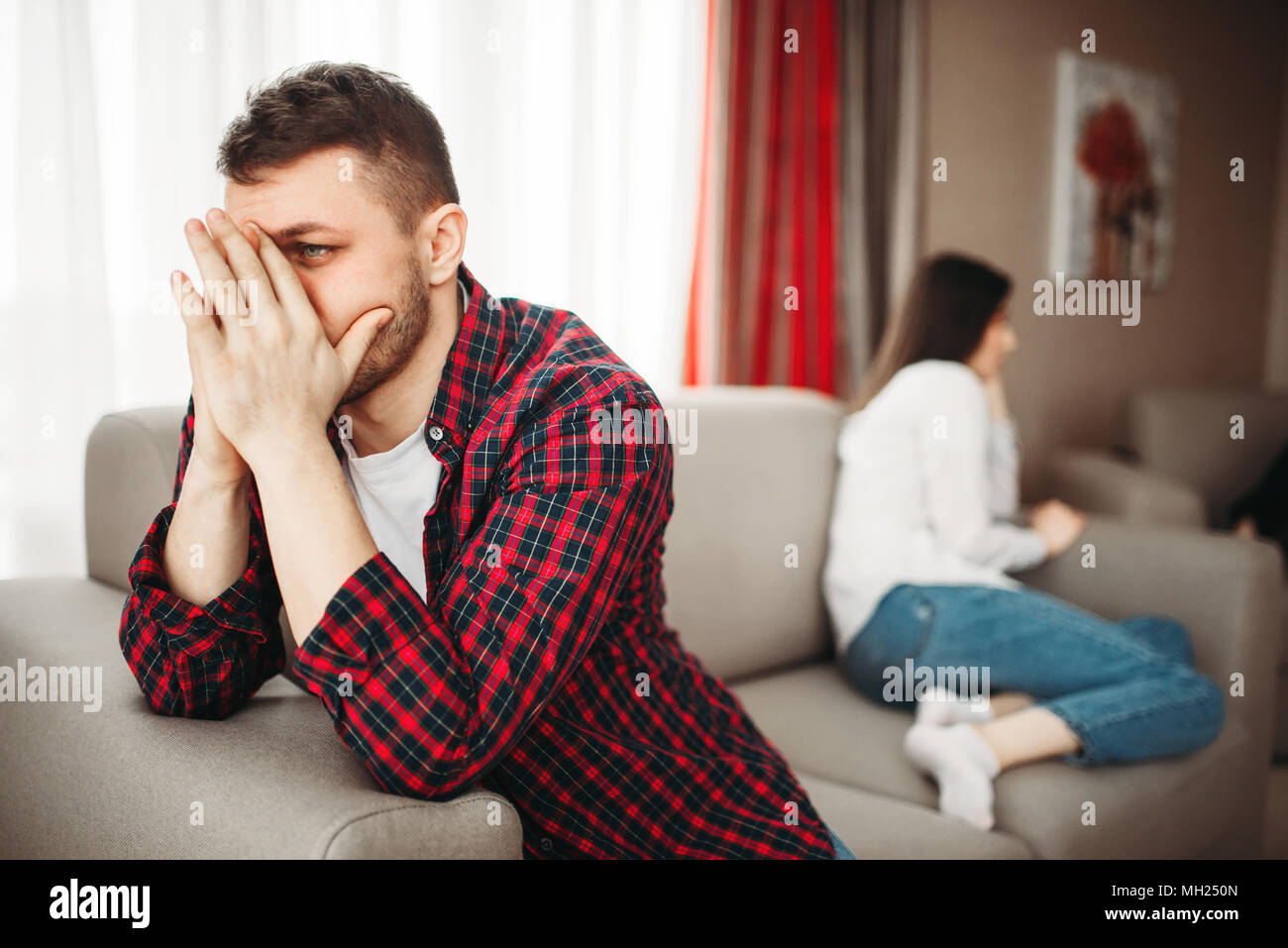 Couple sitting on couch, family conflict Stock Photo