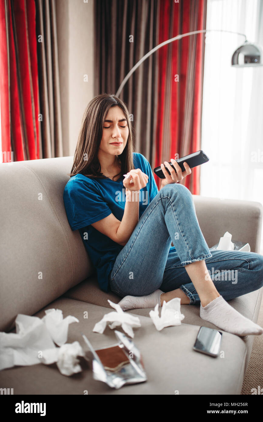 Stressed Woman Sitting On Couch And Eats Sweets Stock Photo