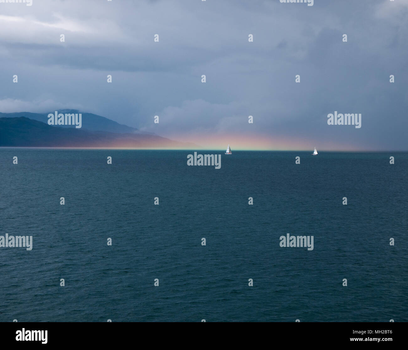 Sailing boats and a sea water rainbow, between Oban and Mull, Scotland, UK Stock Photo