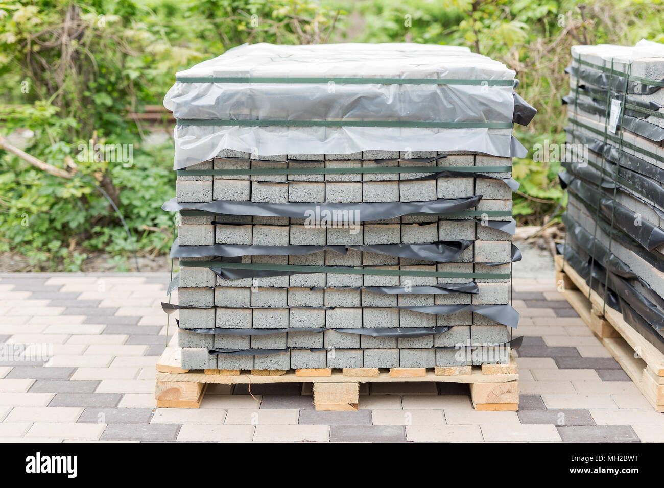 Stack of gray pavement slab on wooden base. Concrete stone paving flag. Isolated on white Stock Photo