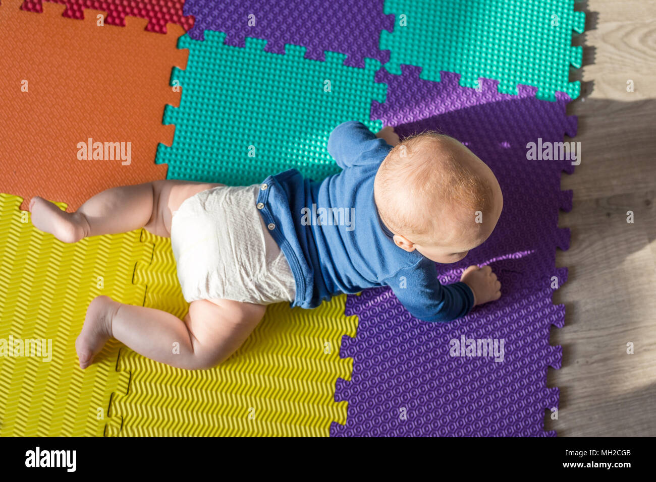 Infant baby boy playing on colorful soft mat. Little child making first  crawling steps on floor. Top view from above Stock Photo - Alamy