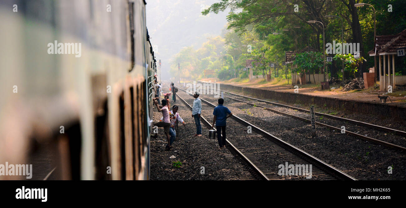 Opportunistic vendors selling supplies to passengers from the tracks through the windows of a stopped train, India Stock Photo