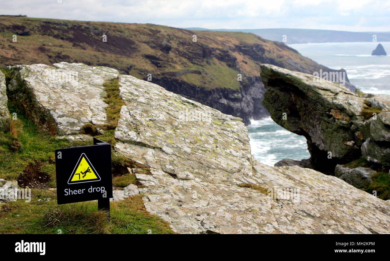 Sign at the top of a high coastal cliff, warning of the danger of a sheer drop. Stock Photo