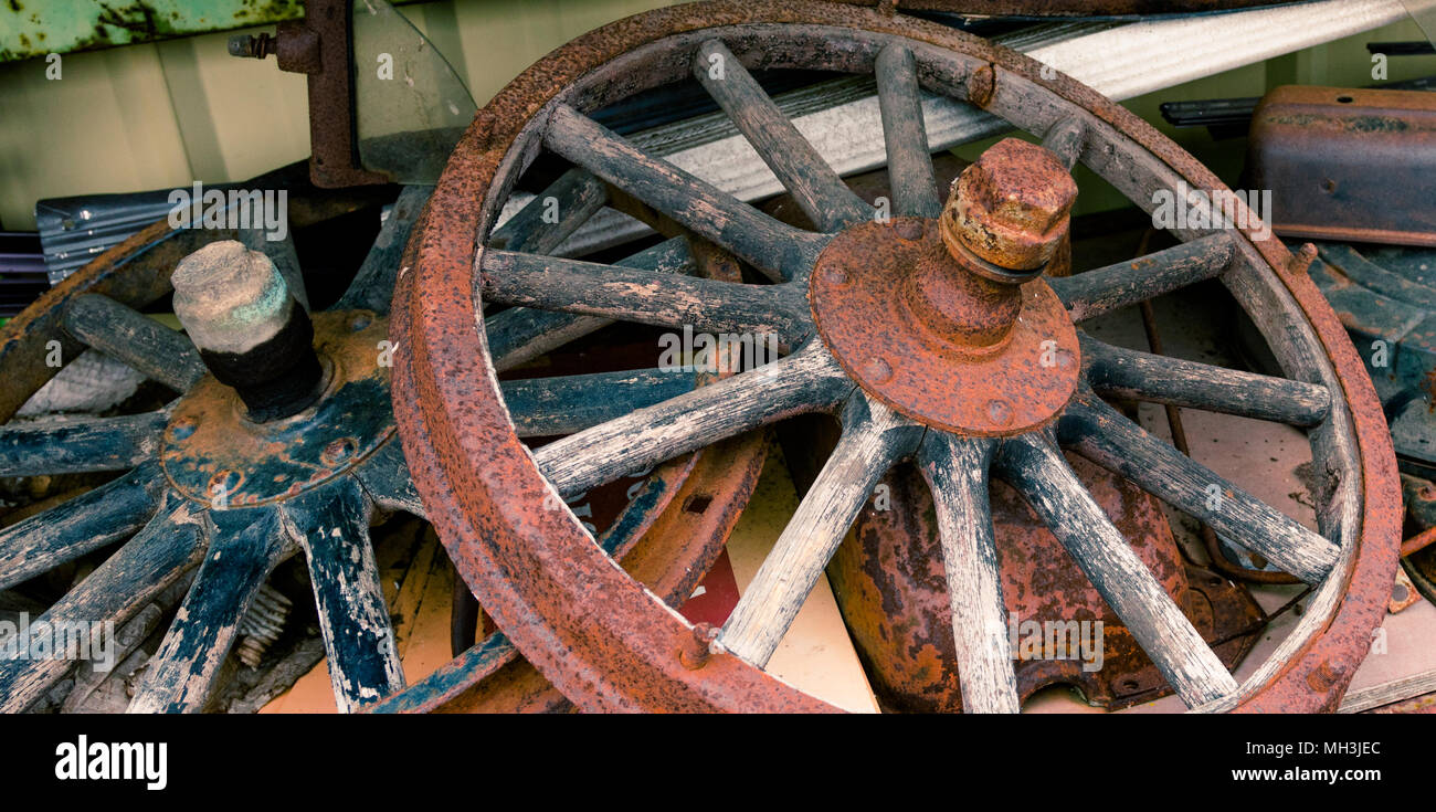 Wooden spoked wheels laying in a pile covered in rust and distress Stock Photo