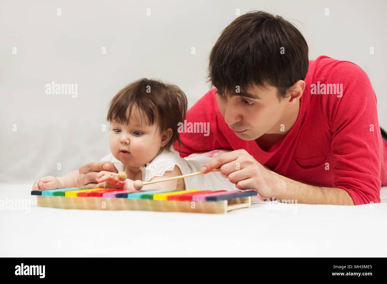 Father and baby girl playing xylophone toy on blanket at home Stock Photo