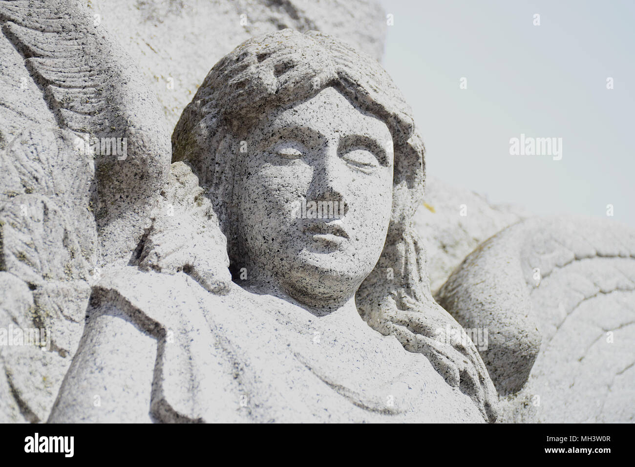 A portion of a statue of an angel in deep meditation with her eyes