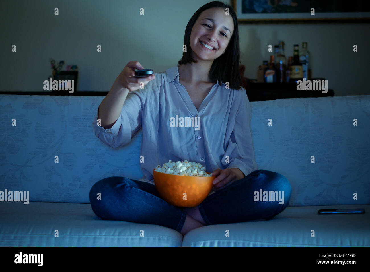 Young woman watching tv sitting on the sofa Stock Photo