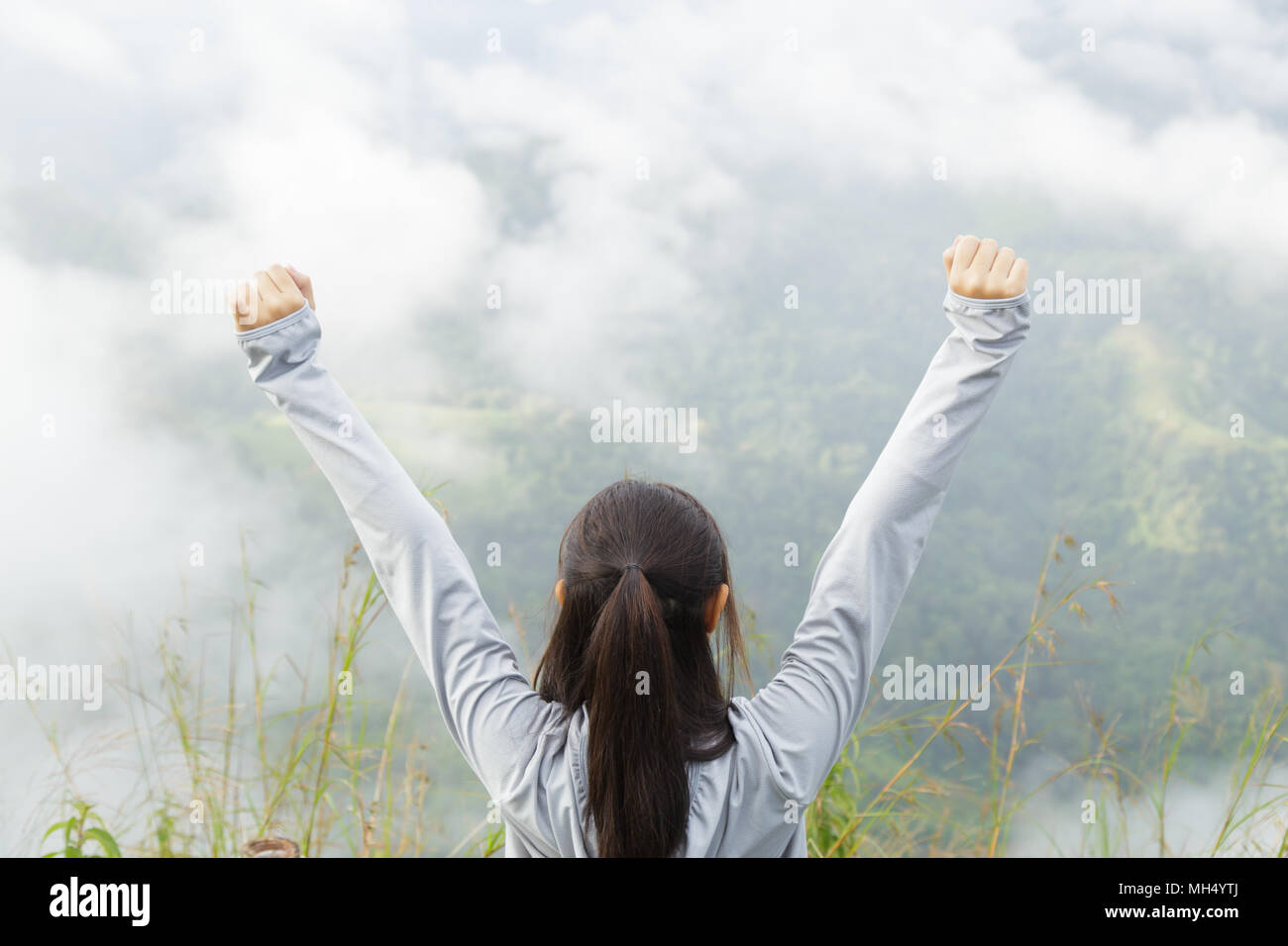 Asia girl relax and refresh on mountain background is a landscape of high mountains, white clouds and fog. Stock Photo