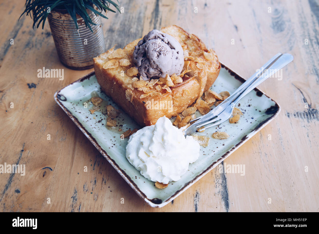 Honey toast and blueberry ice cream with almond topping sprinkle honey on wood table in cafe or restaurant. Stock Photo
