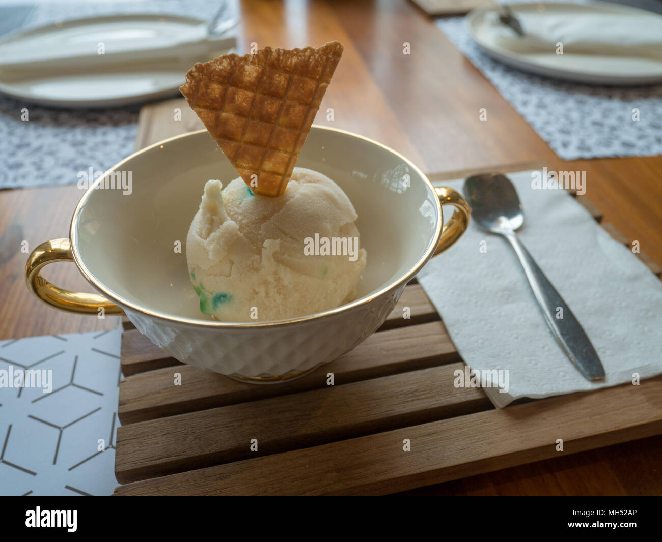 Ice cream vanilla 1 scoop in a cup of luxury with spoon on wooden table in restaurant. Stock Photo