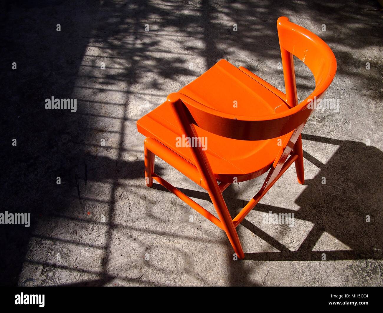 Photo of a newly painted bright orange wooden chair at an outdoor