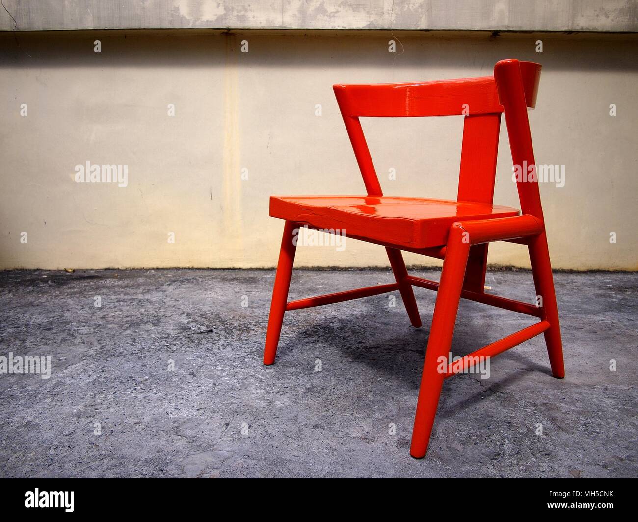 Photo of a newly painted bright orange wooden chair at an outdoor