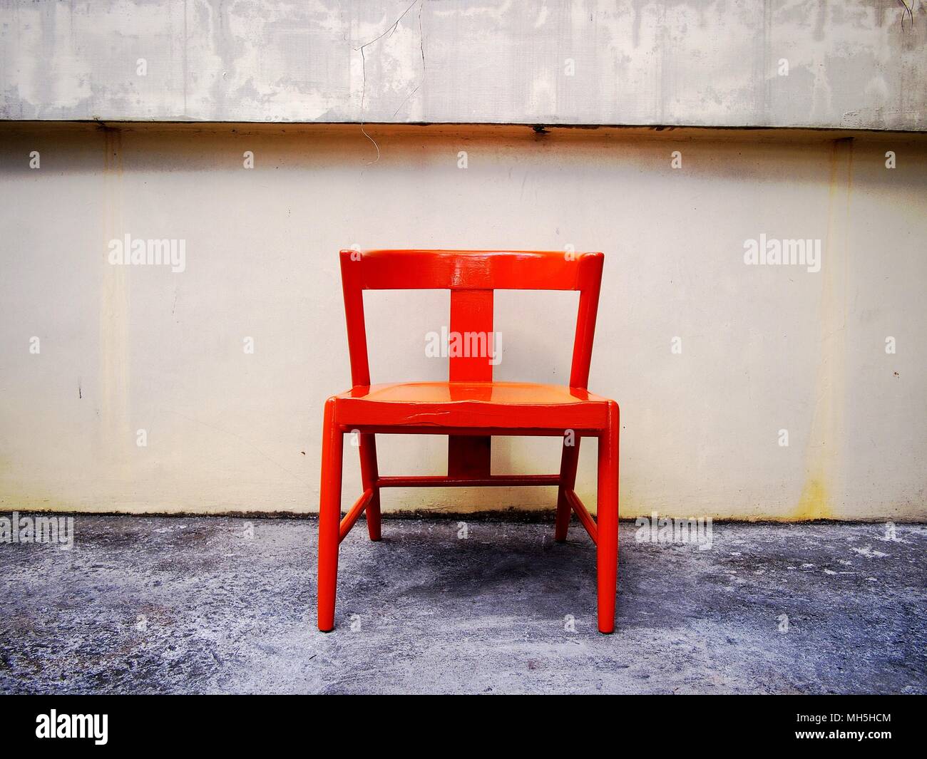 Photo of a newly painted bright orange wooden chair at an outdoor