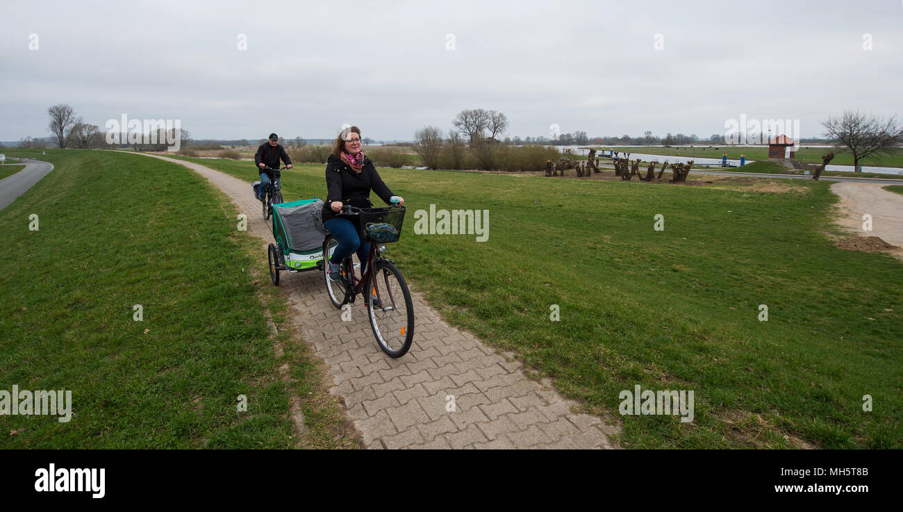 11 April 2018, Germany, Bleckede: Wilfried cycles with his daughter Heike (front) on the dyke along the Elb River. Photo: Philipp Schulze/dpa Stock Photo