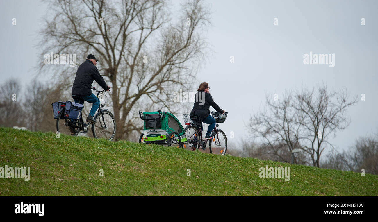 11 April 2018, Germany, Bleckede: Wilfried (L) cycles with his daughter Heike on the dyke along the Elb River. Photo: Philipp Schulze/dpa Stock Photo