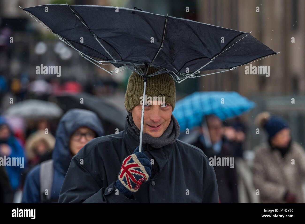 London, UK. 30th April 2018. People struggle with umbrellas as they cross the Millenniium Bridge in the wind and rain. Credit: Guy Bell/Alamy Live News Stock Photo
