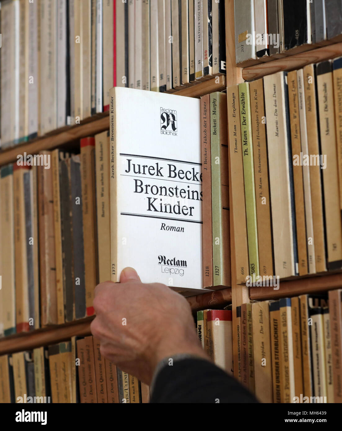 19 April 2018, Rostock, Germany: Bookseller Frank Weisleder stands in front of the book wall with his complete collection of 1380 volumes of the 'Reclam Universalbibliothek', which were published in the GDR between 1963 and 1990 in the Leipzig Reclam publishing house, and pulls out a volume by Jurek Becker. He has been collecting for over 20 years. (to 'Rostock: complete private collection of Reclamheften from GDR time' from 01.05.2018) Photo: Bernd Wüstneck/dpa Stock Photo