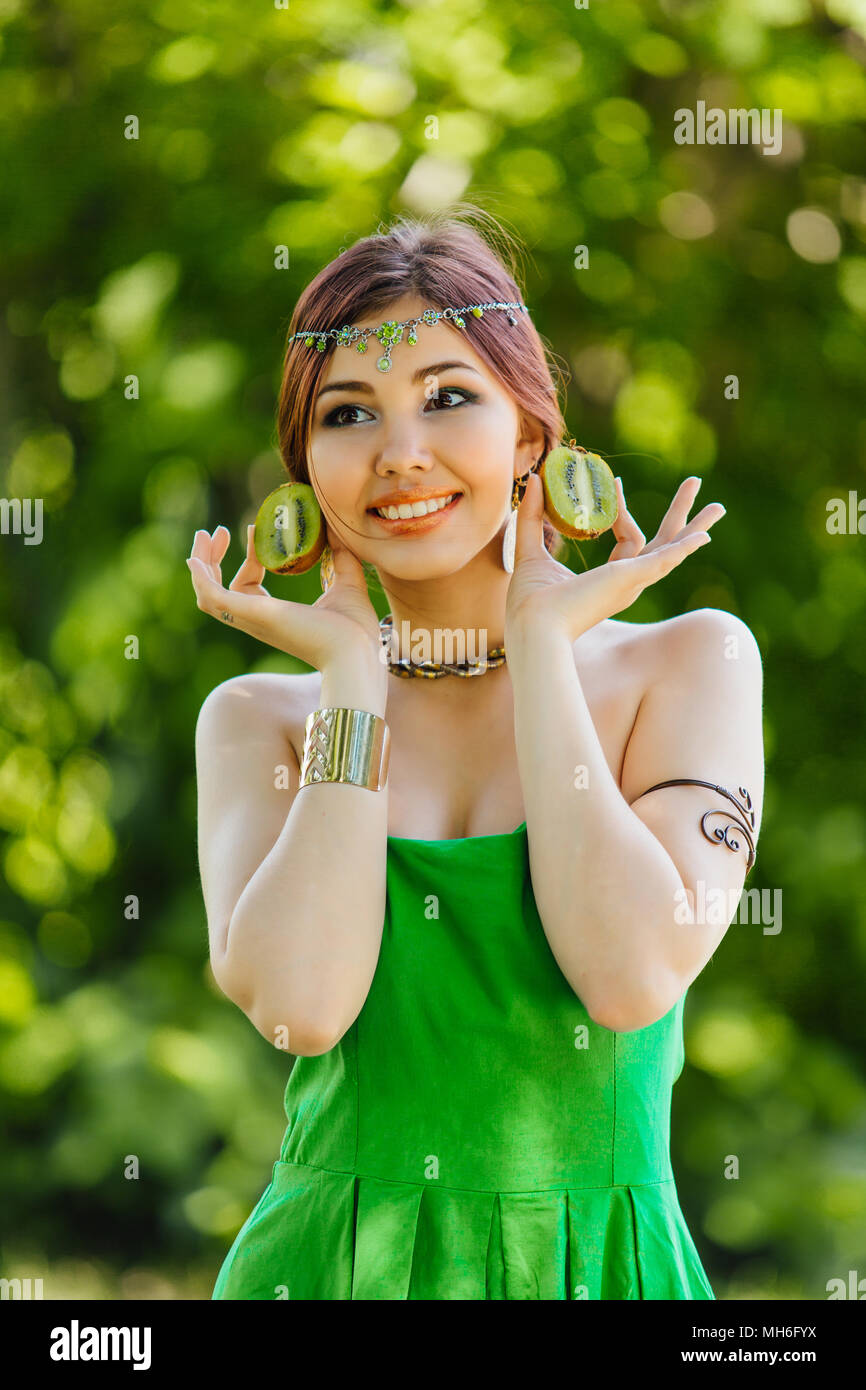 Portrait of a beautiful young asian woman holding two halves of kiwi ...