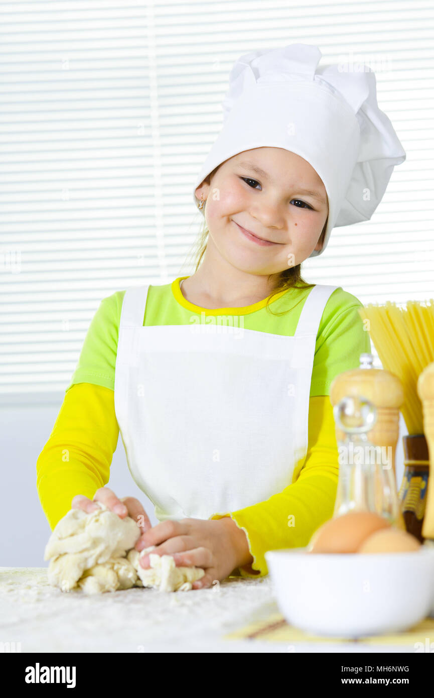 Cute little girl in chef's hat baking cake in the kitchen  Stock Photo