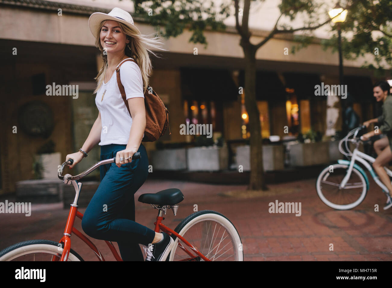 Beautiful caucasian female riding bicycle in the city. Woman cycling and having fun on city street. Stock Photo