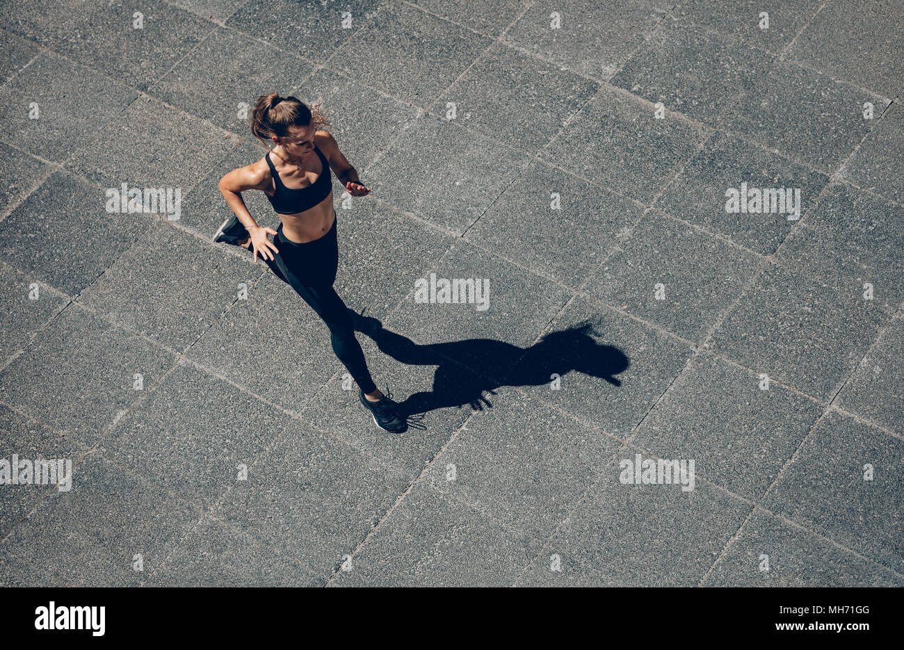 Woman sprinting in the morning outdoors. Top view of female runner working out in the city. Stock Photo