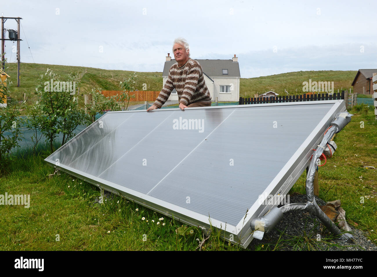 Man outside with his solar water heater that heats his water for his