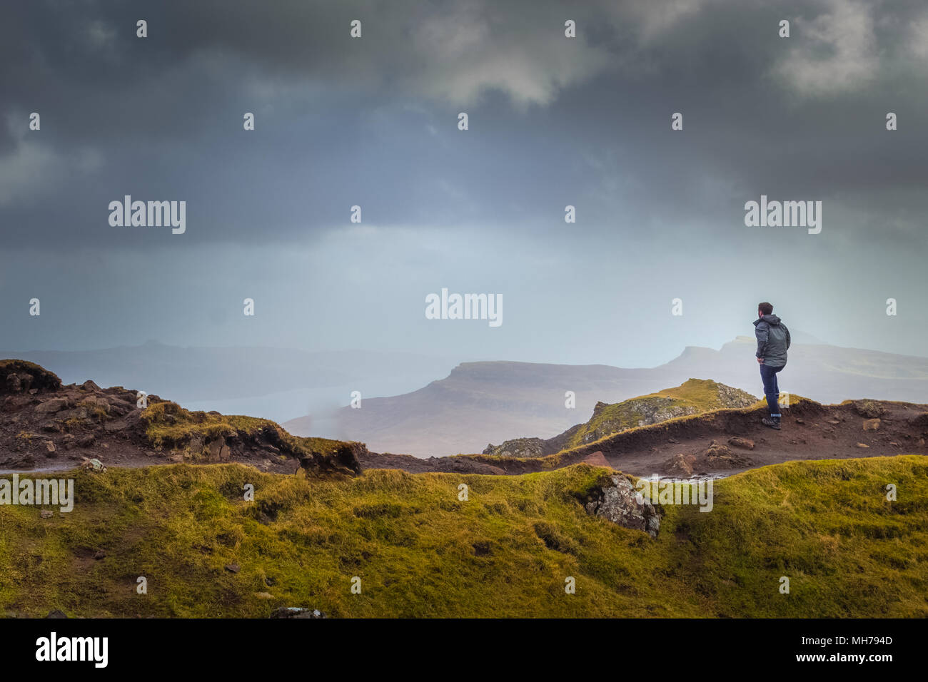 Man In Rain Jacket Looking Into The Distant Landscae From Top of