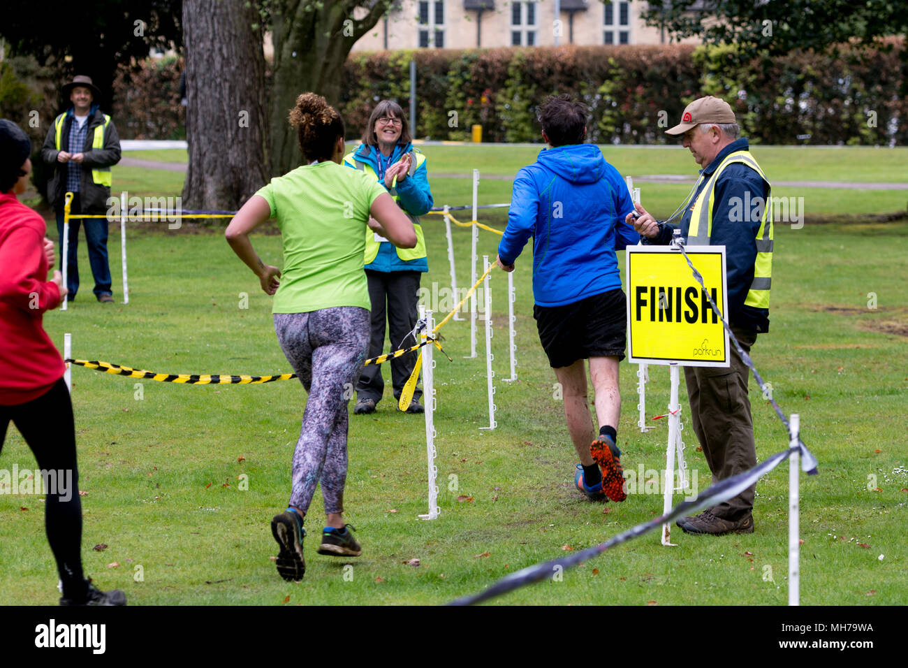 Runners finishing and being timed by a volunteer in the Cirencester parkrun, Gloucestershire, UK Stock Photo