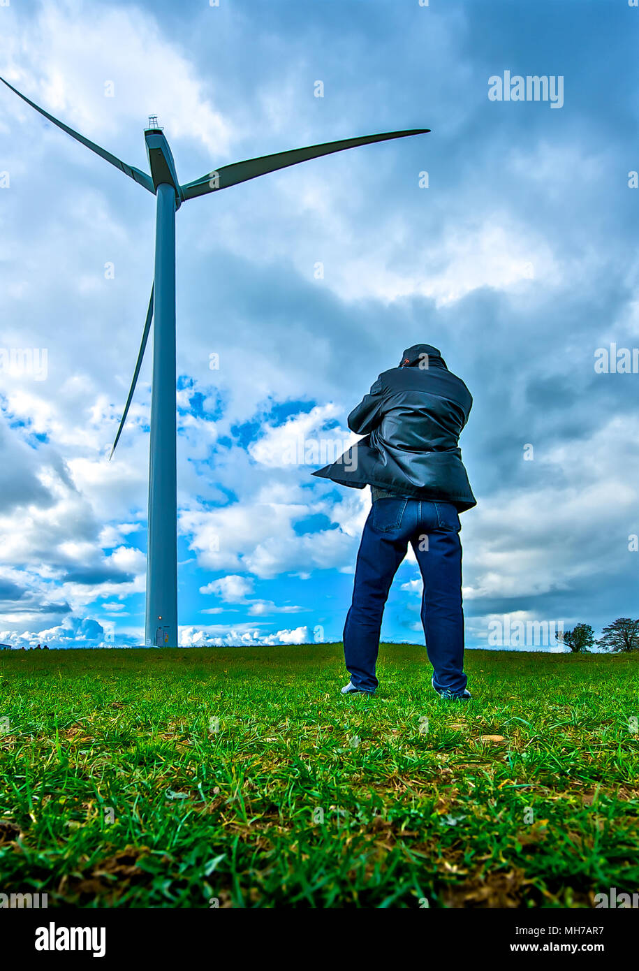 Standing firm for green energy. A man stands near a wind turbine. Stock Photo