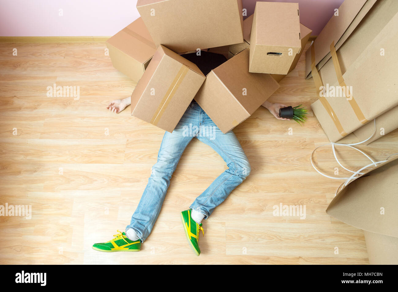 Photo of man in jeans lying under cardboard boxes Stock Photo Alamy