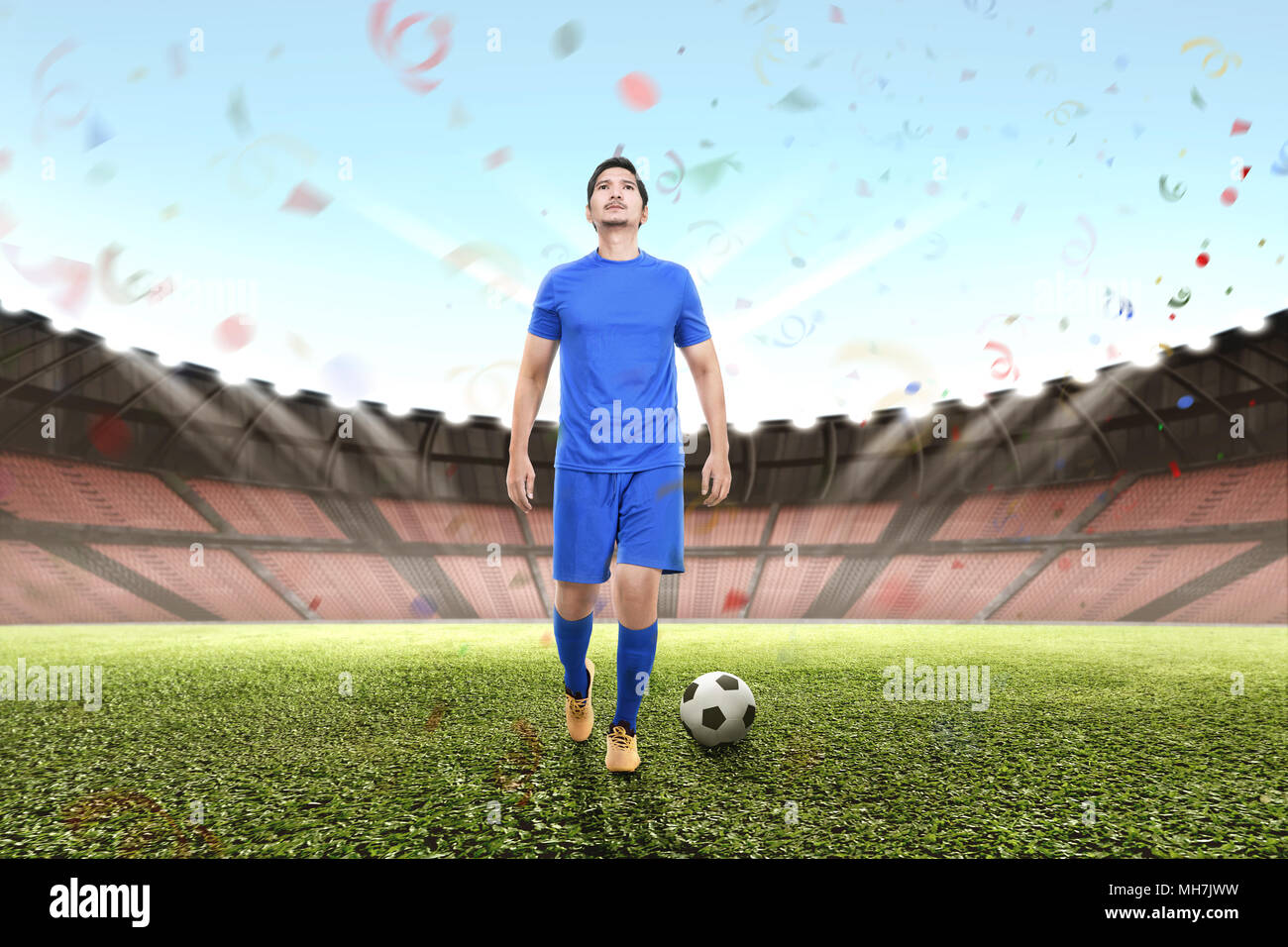 Attractive asian football player man celebrating victory on stadium Stock Photo