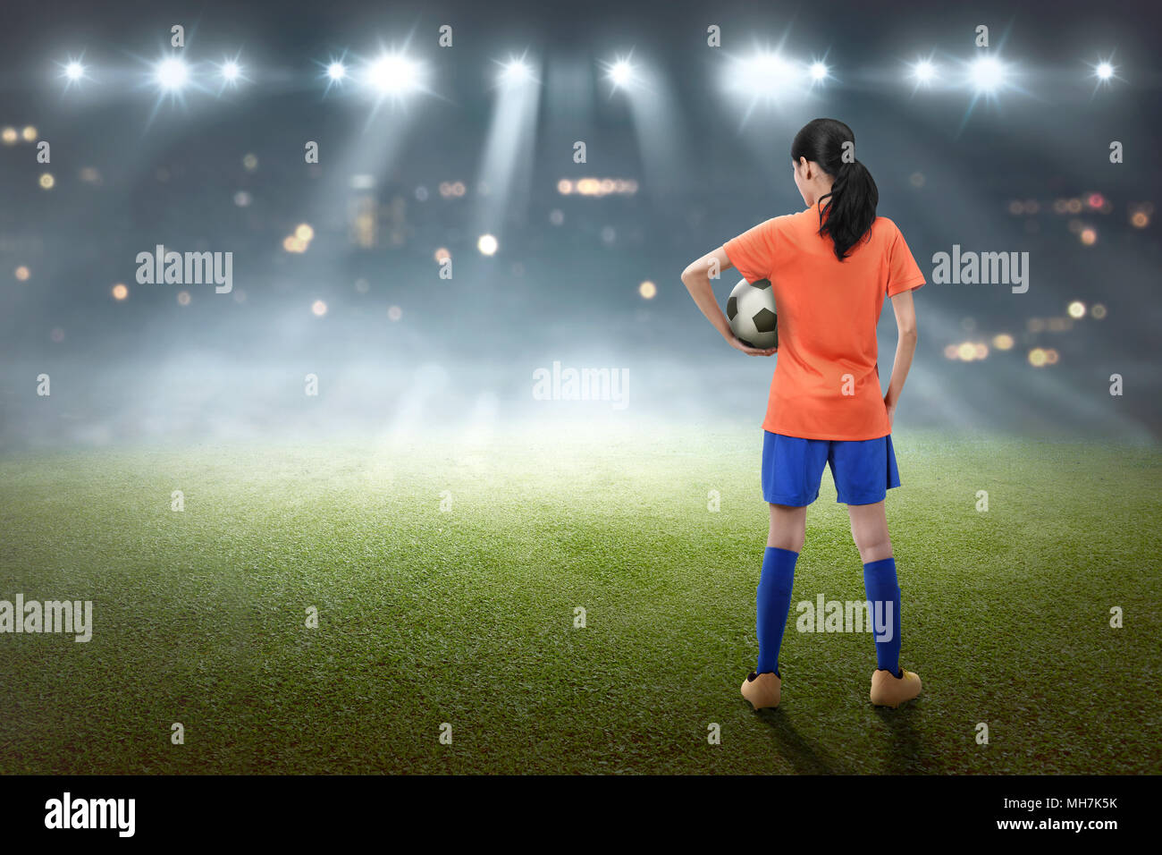 Rear view of asian female footballer with the ball on the field Stock Photo