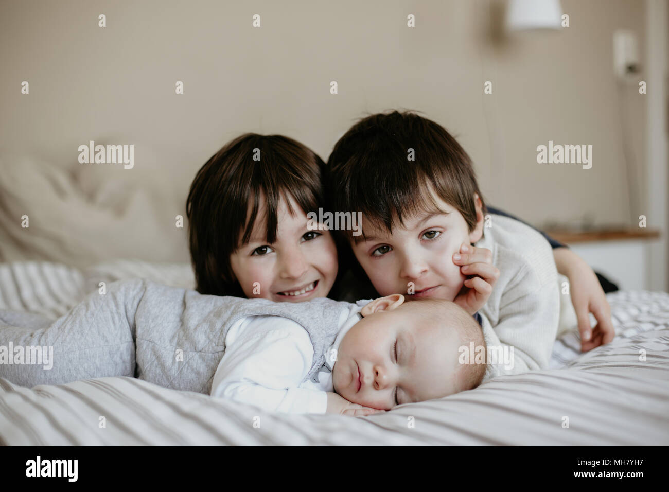 Little baby boy, sleeping in big bed in the afternoon, brothers giving