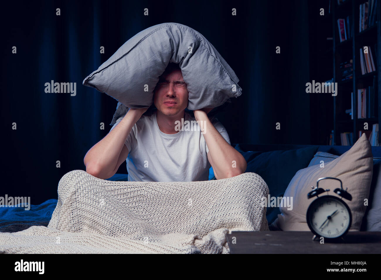 Photo of man with insomnia with pillow on head Stock Photo