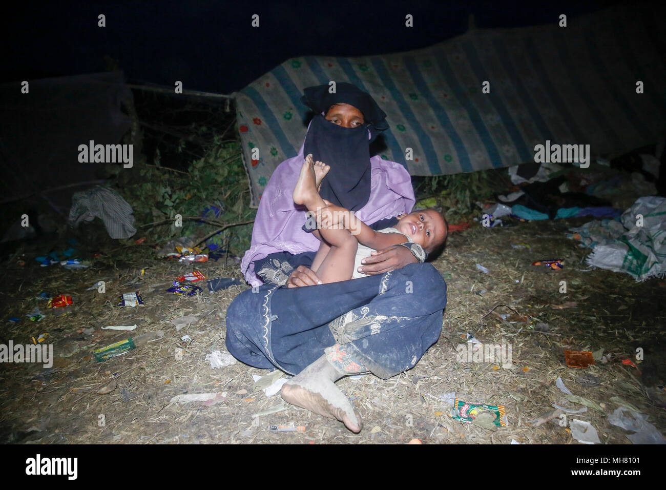 Rohingya refugees take shelter under open sky beside a road at Teknaf