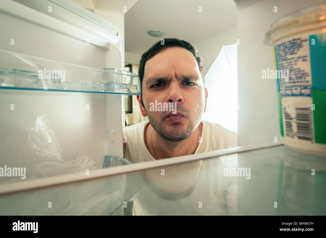 Funny man looking into the fridge Stock Photo